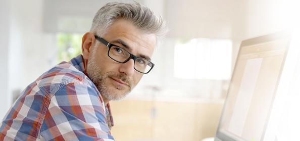 Male looking into the camera, away from his computer screen.